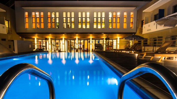 A swimming pool with a modern building in the background. - Onomo Hotel Lome (Lomé)
