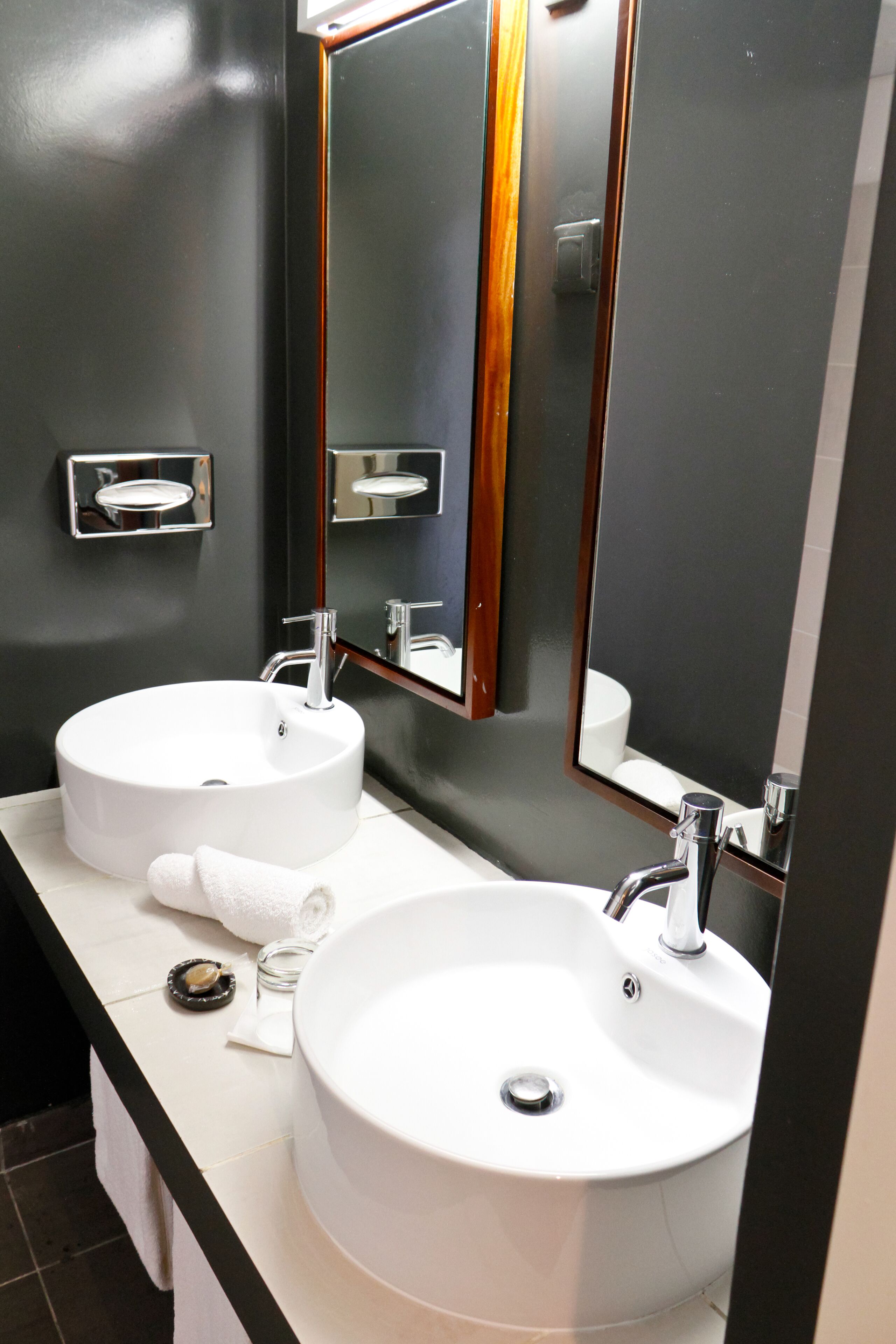 Un baño con dos lavamanos, un espejo y un perchero para toallas.