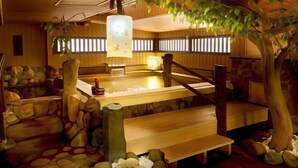 Um onsen japonês tradicional com bancos de madeira, um banho de pedra e um candeeiro suspenso.