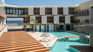Un hotel moderno con piscina central, varios balcones y vista despejada al área de la piscina.