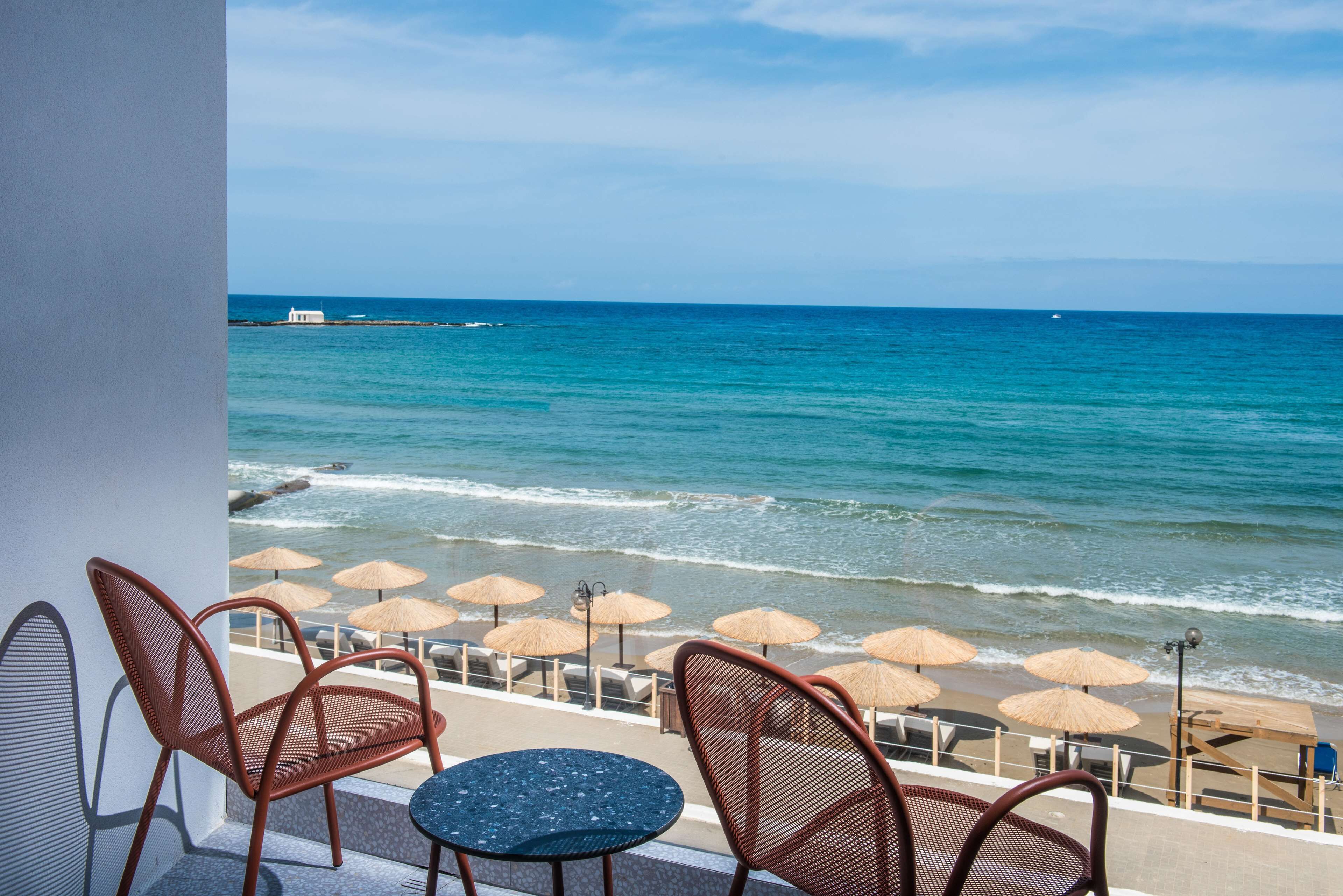 A seaside terrace with chairs and tables, overlooking the ocean.