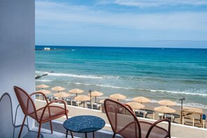 Una terraza frente al mar con sillas y mesas, con vista al océano.