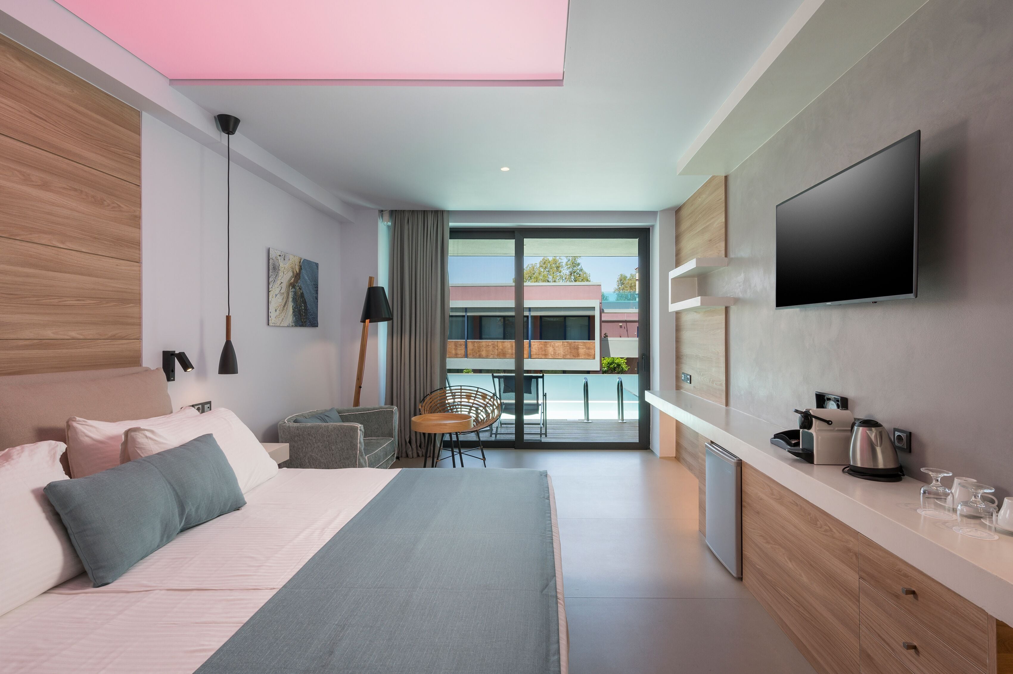 Una habitación de hotel moderna con una cama, un escritorio, un televisor y vistas al exterior.