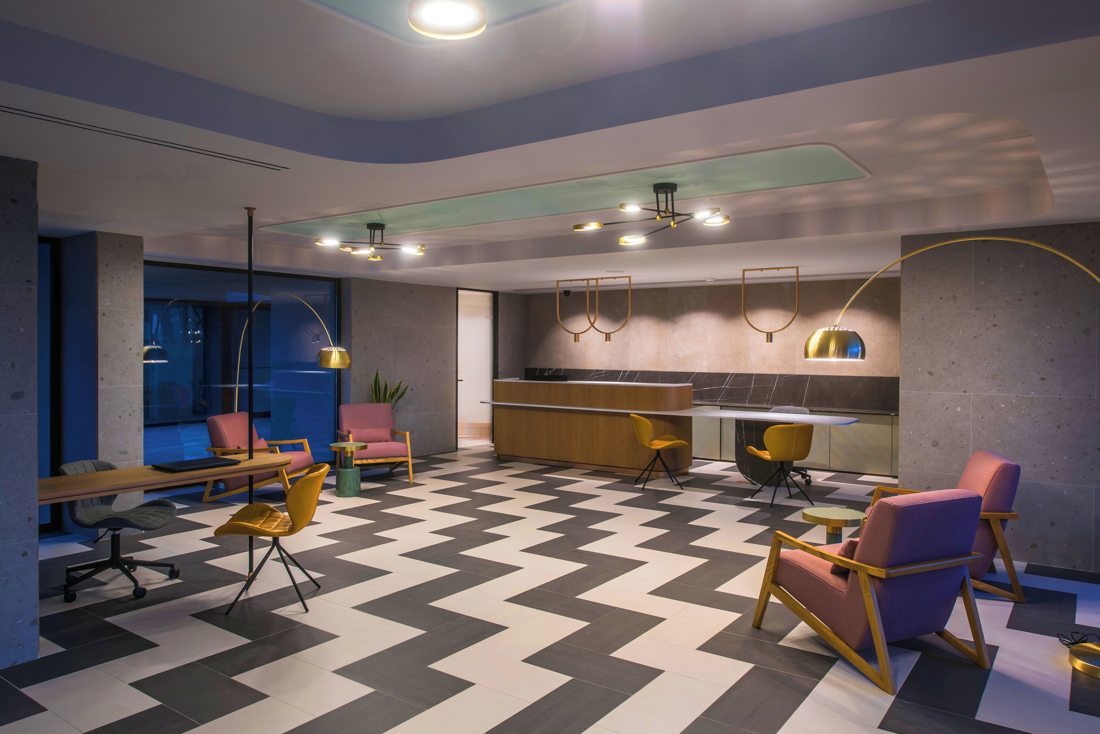 A modern interior with a checkered floor, a reception desk, seating areas, and pendant lighting.