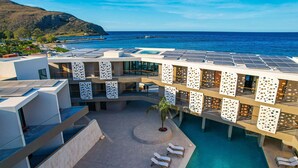 Un resort moderno con zona de piscina, tumbonas y vistas al océano.