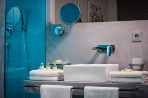 A modern bathroom with a glass shower enclosure, a white sink, and a mirror.