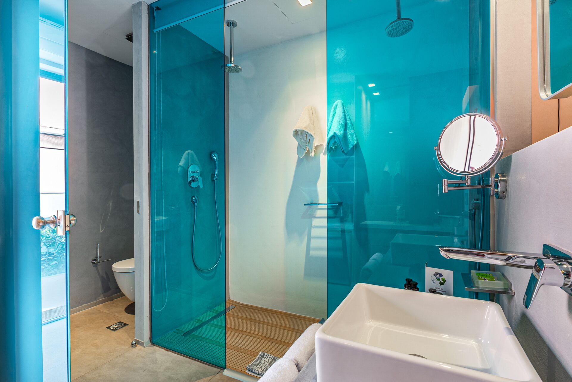 A modern bathroom with a glass-enclosed shower, a white sink, and a mirror.