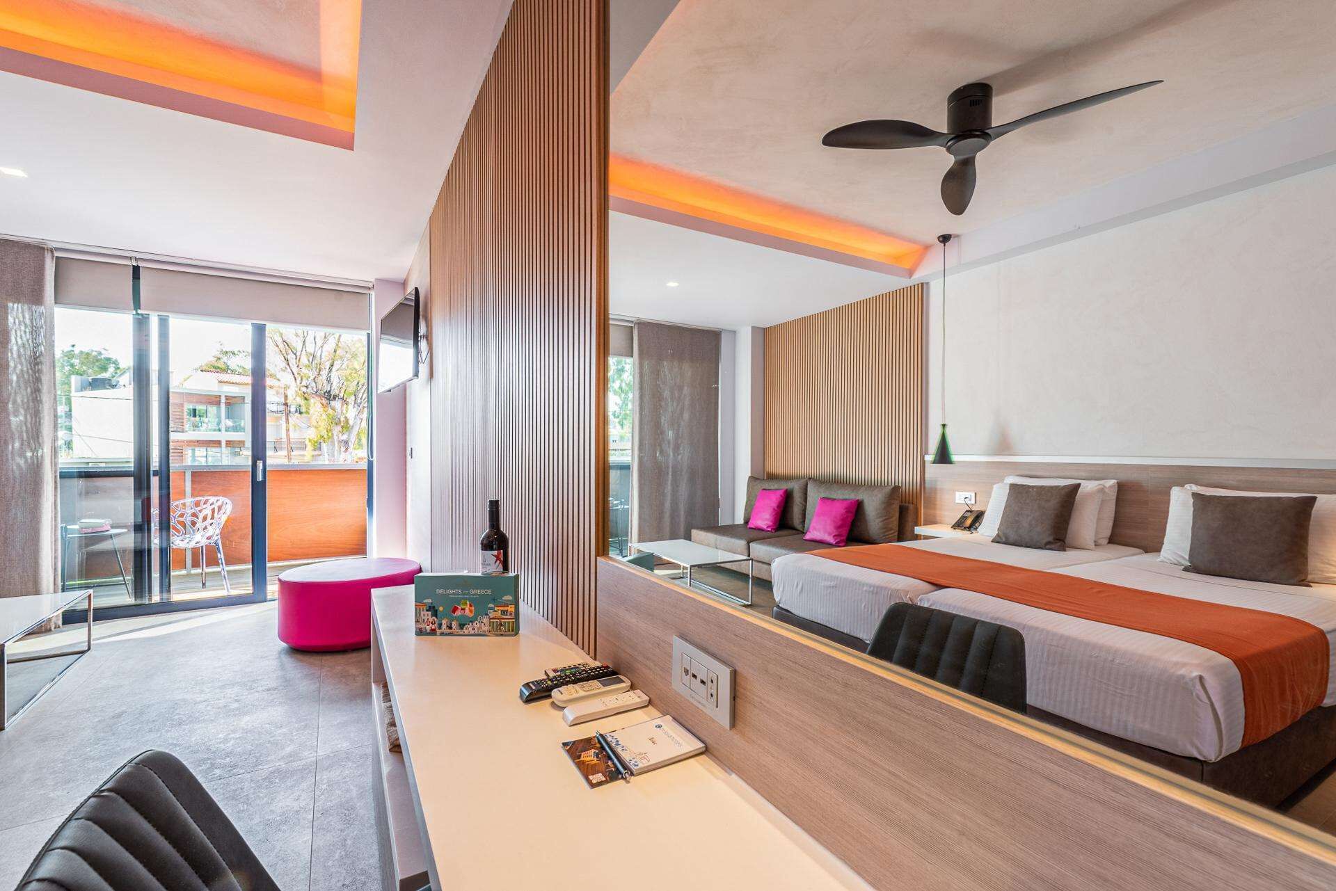 A modern hotel room with a large bed, a desk with a computer, and a view of the outside.