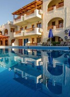 Un hotel de varios pisos con piscina, balcones y zona de estar al aire libre.