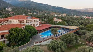 Un resort con piscina, varias construcciones y montañas al fondo.