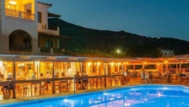 Una piscina con zona de bar y asientos al aire libre, rodeada de edificios con balcones.