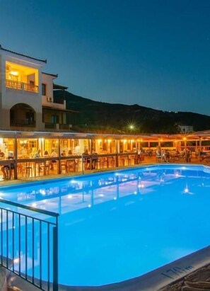 Une piscine dotée d’un bar et d’un espace extérieur aménagé, entourée d’immeubles avec des balcons.