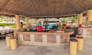 Un espace bar avec une piscine en arrière-plan, entouré de chaises longues et de parasols.