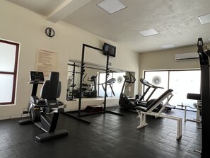 A gym with exercise equipment, a wall-mounted TV, and a window providing natural light. - Canto del Sol Puerto Vallarta All Inclusive (Puerto Vallarta)