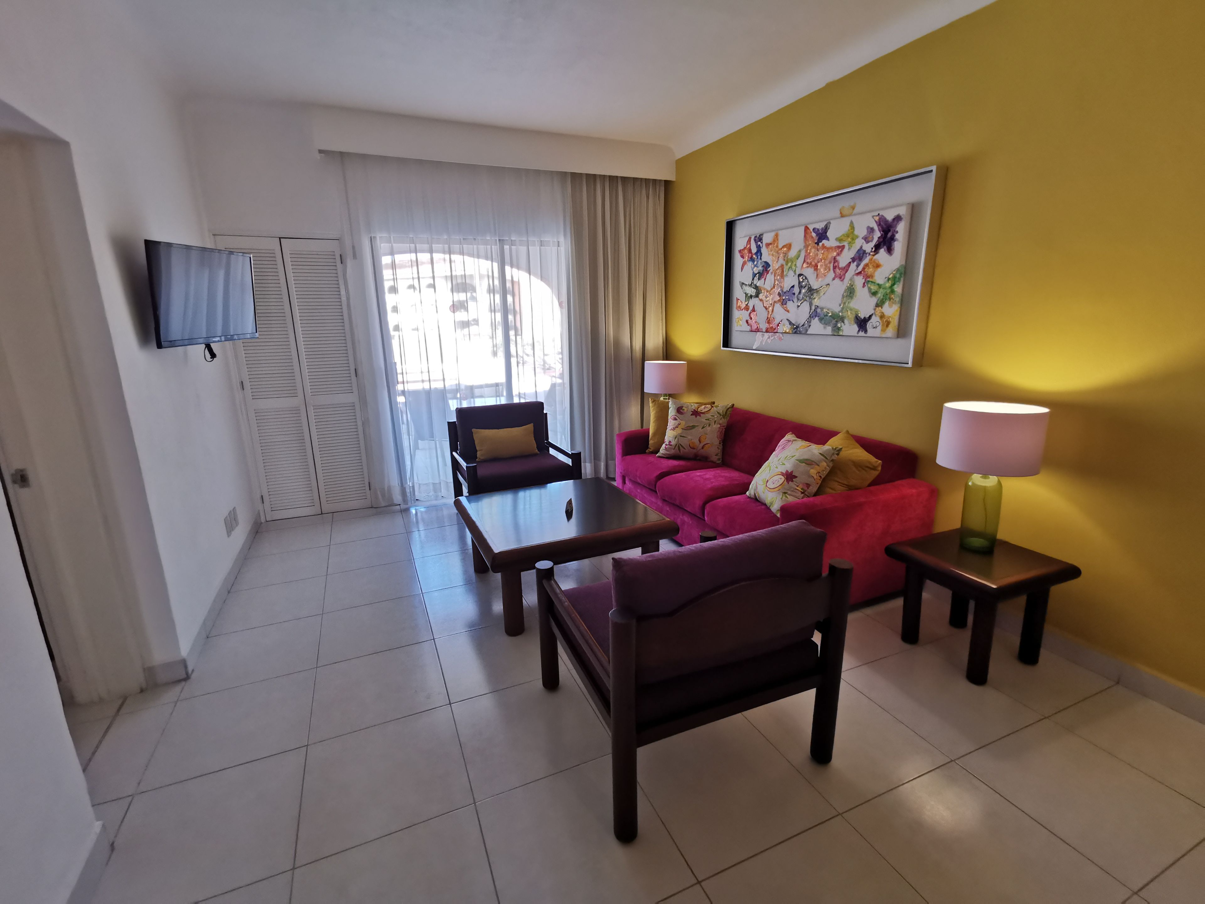 Una sala de estar con un sofá, sillones, una mesa de centro, un televisor y un cuadro en la pared.
