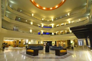 Rebedor d'hotel de diversos nivells, amb una zona d'estar central, múltiples balcons i una imponent escala.