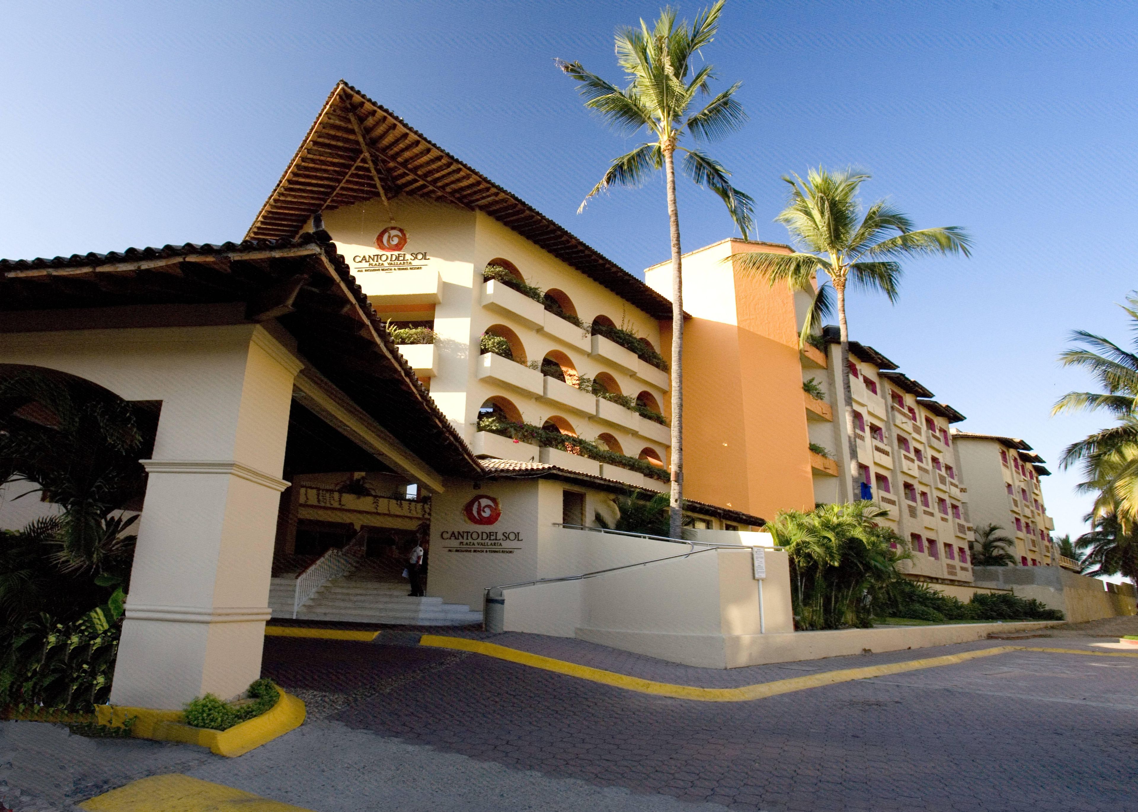 A hotel with a multi-story structure, a prominent entrance with steps, and a clear sky.