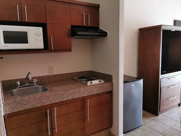 A kitchen with a granite countertop, stainless steel sink, a microwave, a stove, and a refrigerator. - Canto del Sol Puerto Vallarta All Inclusive (Puerto Vallarta)