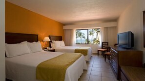 A hotel room with two beds, a TV, a desk, and a window with a view of palm trees. - Canto del Sol Puerto Vallarta All Inclusive (Puerto Vallarta)