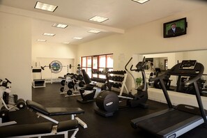 Un gimnasio con diverso equipo de ejercicio, incluyendo cintas de correr, una banca y mancuernas.