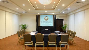 A conference room with a long table, chairs, a projector screen, and a chandelier.