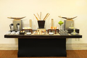 Una mesa de buffet con diversos alimentos, una estación de café y elementos decorativos.