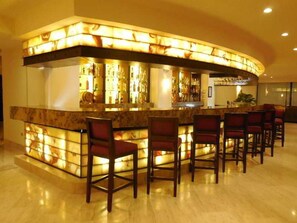 Una zona de bar con una barra curva, diversas opciones de asientos y un suelo pulido.