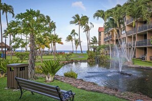 A hotel with a pool, palm trees, a bench, and a building with balconies. - Aston at Papakea Resort (Lahaina)