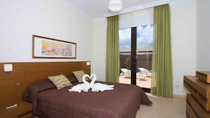 Une chambre d’hôtel avec un grand lit, un tableau au mur et une vue sur l’espace extérieur grâce à une porte coulissante.