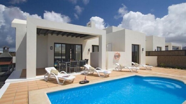 Une maison moderne dotée d’une piscine, d’une façade blanche et d’un patio couvert.