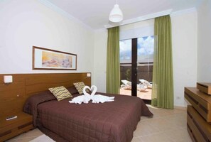 Ein Hotelzimmer mit einem großen Bett, einem Bild an der Wand und Blick auf den Außenbereich durch eine Schiebetür.