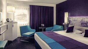 A hotel room with a bed, two chairs, a small table, a desk, a lamp, and a window with curtains. - Hôtel Mercure Marseille Centre Vieux-Port (MARSEILLE)