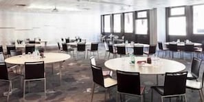 A conference room with multiple round tables and chairs, large windows, and a modern interior design. - Hôtel Mercure Marseille Centre Vieux-Port (MARSEILLE)