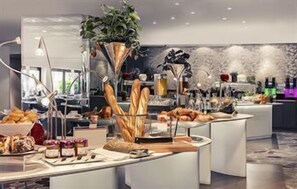 A buffet setup with various food items and a decorative plant. - Hôtel Mercure Marseille Centre Vieux-Port (MARSEILLE)
