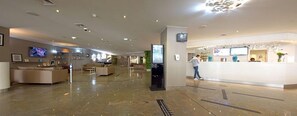A modern hotel lobby with a reception desk, seating area, and digital screens. - Hôtel Mercure Marseille Centre Vieux-Port (MARSEILLE)