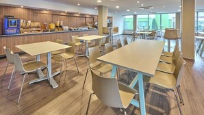 A modern dining area with tables and chairs, a counter with food and drink dispensers, and large windows. - City Express by Marriott Toluca (Toluca)