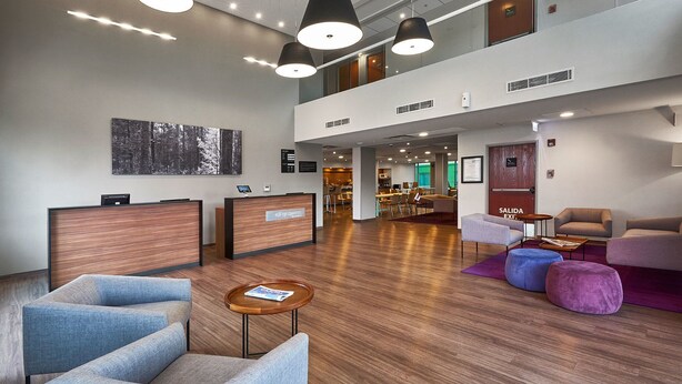 A modern lobby with seating areas, a reception desk, and a staircase leading to an upper level. - City Express by Marriott Toluca (Toluca)