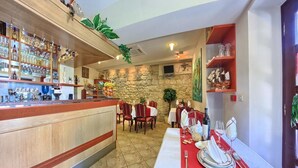A restaurant with a bar, stone walls, wooden furniture, and a variety of bottles. - Trogir (Trogir)