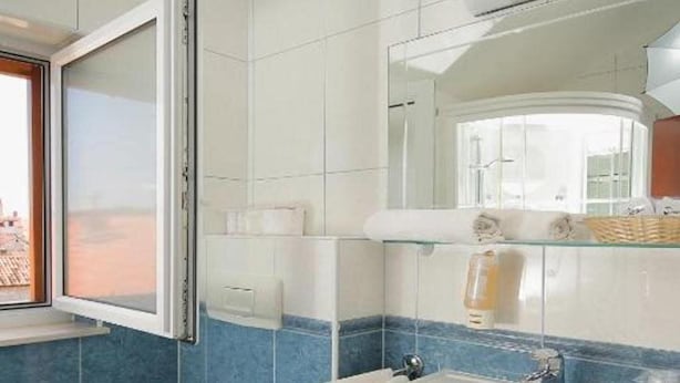 A bathroom with a toilet, sink, and window. - Trogir (Trogir)