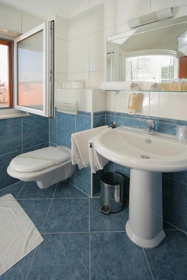 A bathroom with a toilet, sink, and window. - Trogir (Trogir)