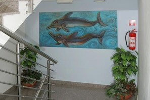 A staircase with metal railings, a wall-mounted fire extinguisher, and two potted plants.