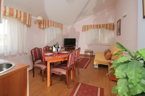 A dining area with a table and chairs, a television, and a sofa.