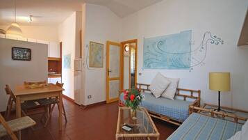 Un ambiente compatto con angolo ristoro, divano, tavolino e letto.