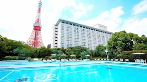A hotel with a swimming pool, a red tower in the background, and lush greenery. - Tokyo Prince (Tokyo)