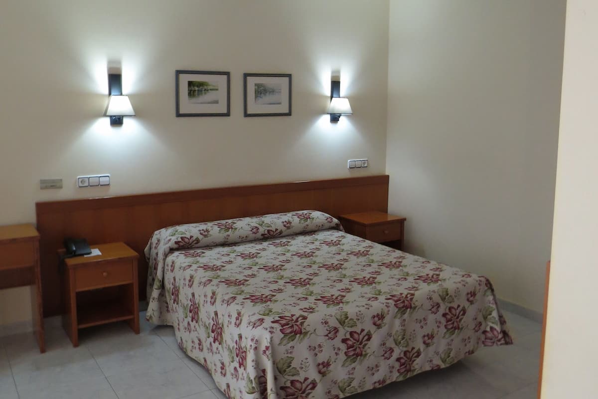 Een slaapkamer met een bed, twee nachtkastjes, en twee wandlampen.