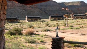 A desert landscape with traditional-style buildings, a stone wall, and a lamp post. - Canon Village (Fish River Canyon)