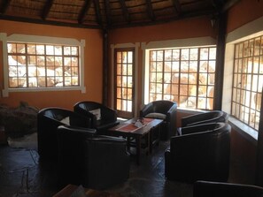 Cozy retreat with a thatched roof, large windows, and a comfortable seating area.