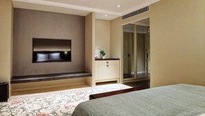 A bedroom with a bed, a TV mounted on the wall, a wardrobe, and a bathroom visible through a glass door. - Beijing Grand Hotel (Beijing)