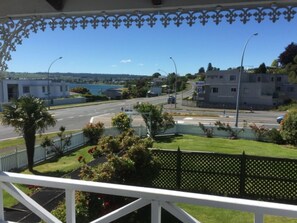 Vista desde un balcón sobre una calle con una gasolinera Mobil, un edificio de fachada blanca y un cuerpo de agua a lo lejos.