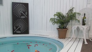 Ein Pool mit weißer Liegefläche, einem Blumentopf und einem dekorativen Wandelement.